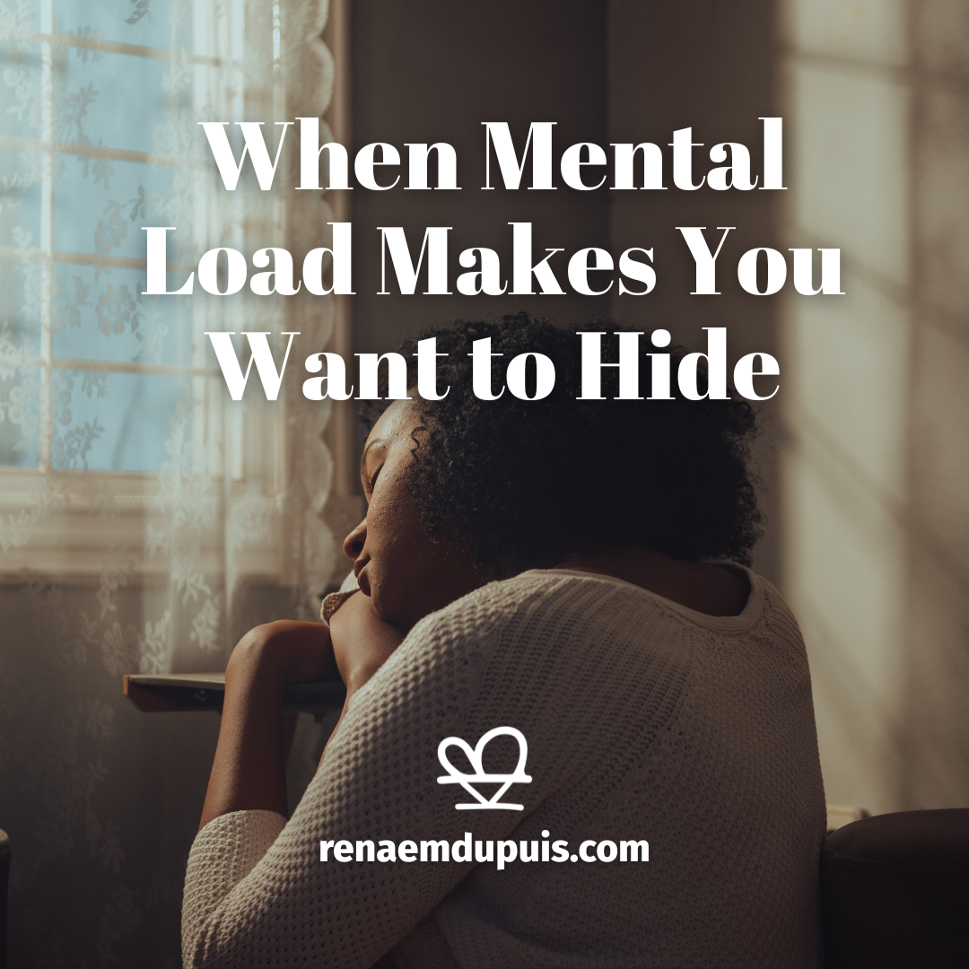 Person leaning on a table by a sunlit window, head resting, with the title 'When Mental Load Makes You Want to Hide' overlaid and the site logo/URL at the bottom (renaemdupuis.com).